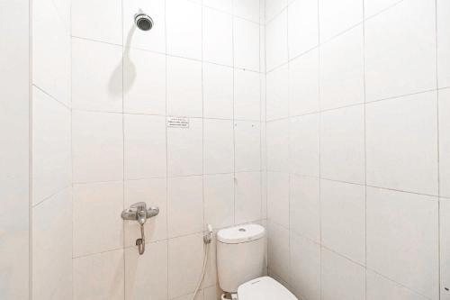 a white tiled bathroom with a toilet and a shower at RedDoorz Syariah Near Jam Gadang Bukit tinggi 2 in Bukittinggi
