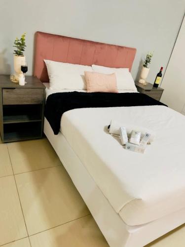 a bedroom with a large white bed with a pink headboard at Rooibok Gardens in Mokopane