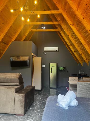 a room with a vaulted ceilings and a room with a refrigerator at Chalé Rio Capetinga 02 in Anchieta