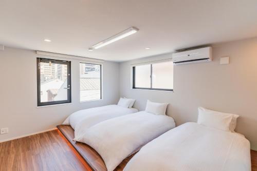 two beds in a room with white walls and windows at Flower Base Botan in Fukuoka