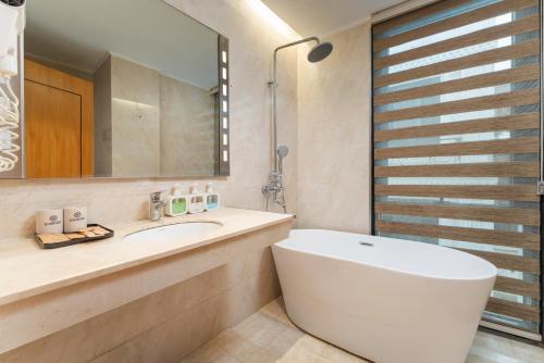 a bathroom with a white tub and a sink at HALO HANOI HOTEL in Hanoi