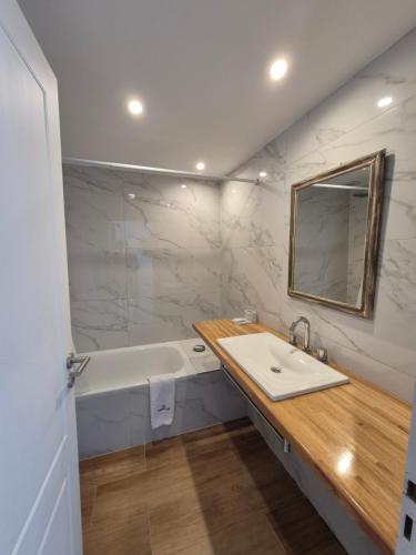 a bathroom with a sink and a tub and a mirror at VIENTOS apartments in Villa Gesell