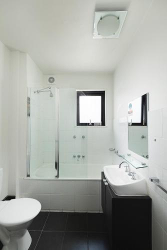 a white bathroom with a sink and a shower at Sora East Melbourne in Melbourne