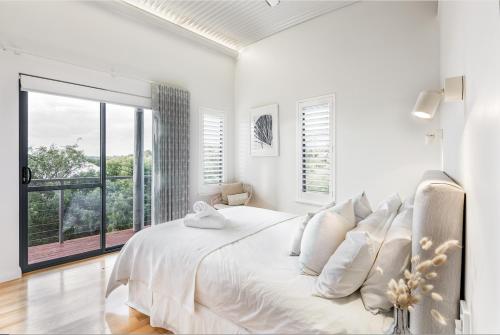 a white bedroom with a bed and a large window at Ocean Blue - Gnarabup NEW in Gnarabup