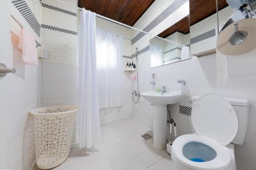 a white bathroom with a toilet and a sink at Tov Stay Atti in Pyeongtaek