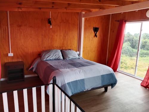 a bedroom with a bed in a room with a window at Cabaña El ulmo in Quelalmahue