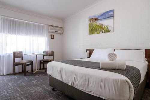 a hotel room with a large bed and a table at Bayview Motel in Esperance