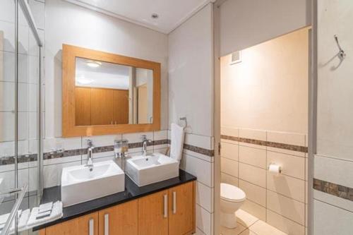 a bathroom with two sinks and a toilet and a mirror at Manhattan Escape Suite By Ezey Tours in Cape Town