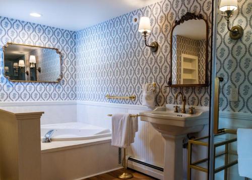 a bathroom with a tub and a sink and a bath tub at Inn at Pleasant Lake in New London