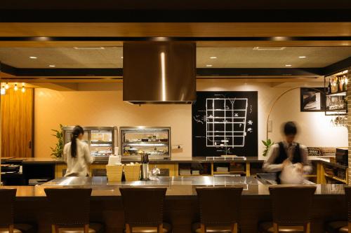 two people walking in a restaurant with a counter at Sakura Terrace The Atelier in Kyoto