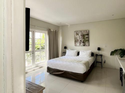 a bedroom with a bed with white sheets and a window at Casa Artista By Kresna Hospitality in Seminyak