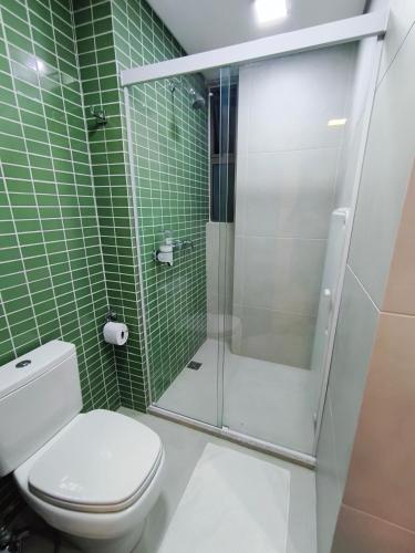 a green tiled bathroom with a toilet and a shower at Flat Luxo em Boa Viagem - 5min do Aeroporto - perto da praia - Wi-Fi 500mb - check-in 24h in Recife