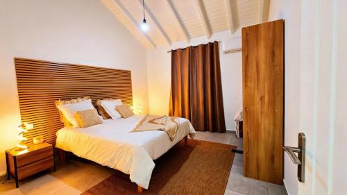 a bedroom with a large bed with a wooden headboard at Villa Kynoa 4 étoiles in Saint-François