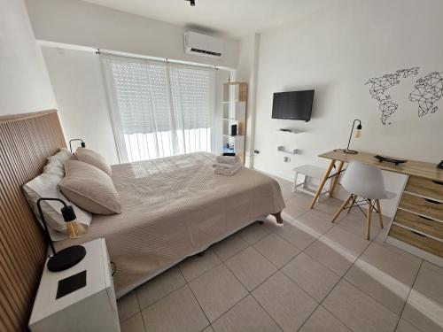 a bedroom with a bed and a desk with a computer at Luminoso y cálido atardecer in Ramos Mejía