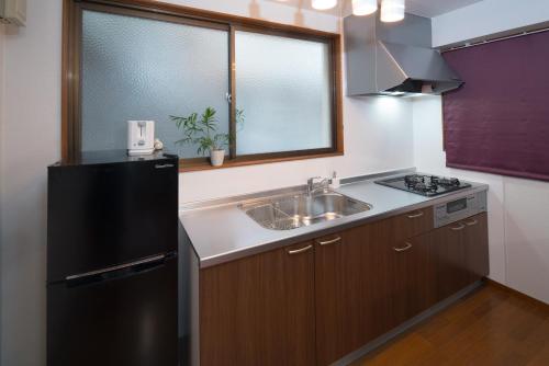 a kitchen with a sink and a black refrigerator at 禅 Zen 鹿児島 フロア貸切 中央駅徒歩14分 in Yamashitachō