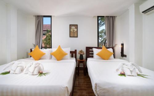 two beds in a room with white and orange pillows at Stay Siem Reap in Siem Reap