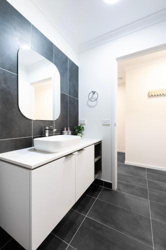 a bathroom with a white sink and a mirror at Oak & Ivy on Windsor in Williamstown