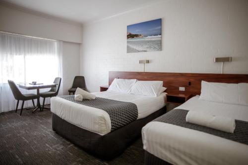 a hotel room with two beds and a table at Bayview Motel in Esperance