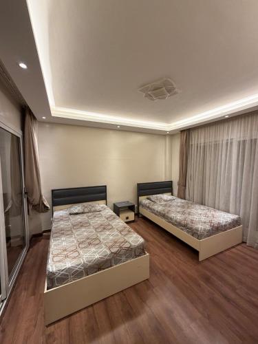 two beds in a room with wooden floors at Modern 4BR 3Bath Stylish Spacious in Madinaty