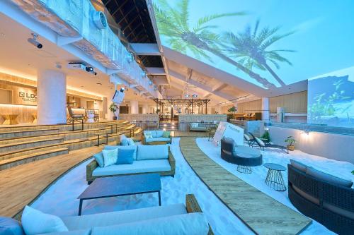 a lobby with couches and chairs and palm trees at GRAND HOSTEL LDK Tokyo Nishikasai -GRAND OPENING In May 2025- in Tokyo