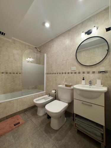 a bathroom with a toilet and a sink and a mirror at Campana Suites Becerra in Campana