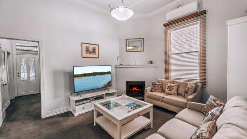 a living room with a couch and a tv at Family Cottage in Bendigo