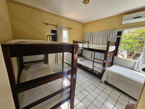a room with three bunk beds and a window at São Luís Hostel - Dormitórios Compartilhados e Quartos Privativos in São Luís