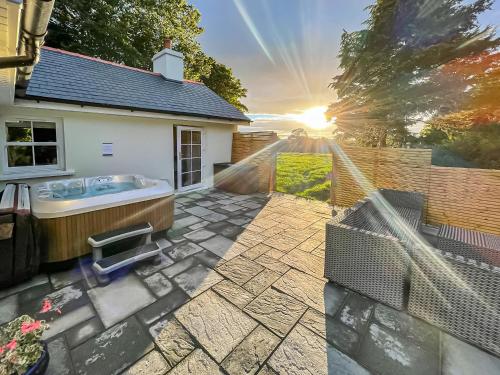 a backyard with a hot tub and a fence at Bumblebee Cottage-Uk39918 in Ballakinnag