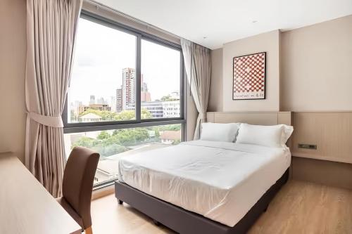 a bedroom with a bed and a large window at Tierra Residences in Bangkok in Bangkok