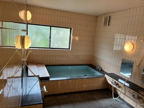 a bathroom with a hot tub and a window at Fukuzawa Ryokan - Vacation STAY 39918v in Sakai