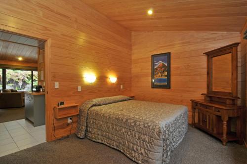 a bedroom with a bed and a wooden wall at Creel Lodge in Turangi