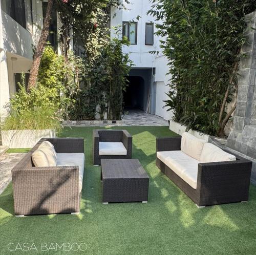 a patio with chairs and couches on grass at Casa Bamboo in Mexico City