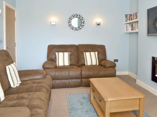 a living room with a brown couch and a coffee table at Anchor's Away in Filey