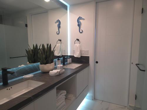 Ein Badezimmer mit Waschbecken und Spiegel mit Seepferdchen an der Wand in der Unterkunft Encanto de Cortes in Playa Encanto