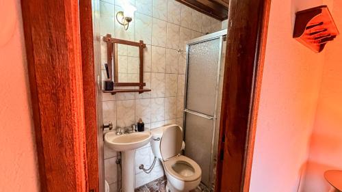 a small bathroom with a toilet and a sink at Chalés Lua de Mel in Monte Verde
