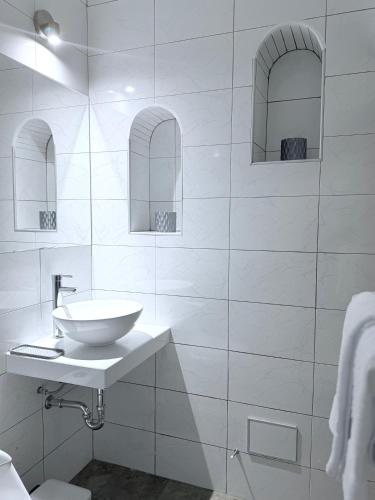 a white bathroom with a sink and two mirrors at Posada Del Corregidor in Cajamarca
