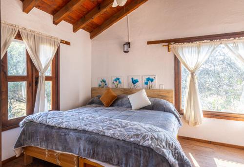 a bedroom with a bed in a room with windows at Cabaña El Sitio in Huasca de Ocampo