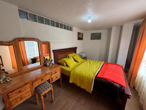a bedroom with a bed with a dresser and a mirror at Hospedaje Las Bromelias - Departamento Familiar in Papallacta