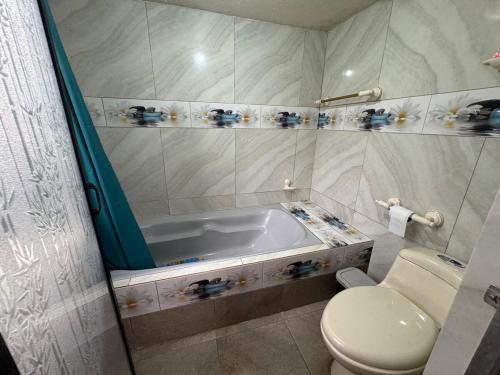 a bathroom with a bath tub and a toilet at Hospedaje Las Bromelias - Departamento Familiar in Papallacta