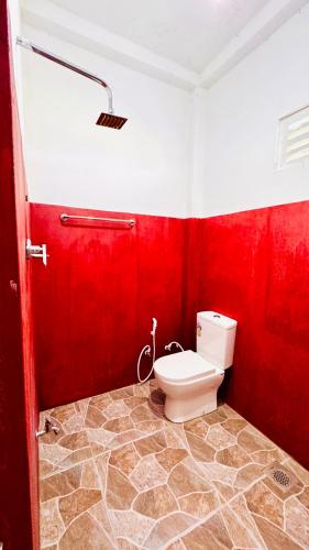 a red bathroom with a toilet and a red wall at Willow Nest Inn in Mahiyangana