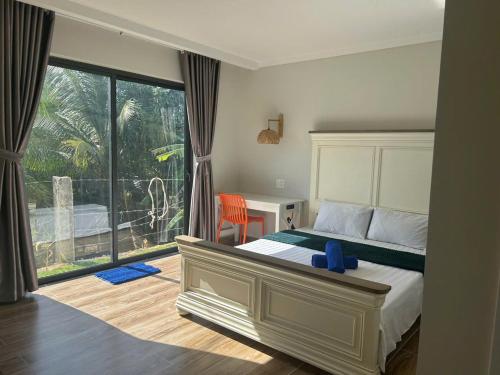 a bedroom with a bed and a desk and a window at Lisa House Phu Quoc in Phú Quốc