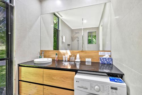 a bathroom with a sink and a washing machine at Under the Pecans - 2BR Retreat with Peaceful Scenic Views in Woombye