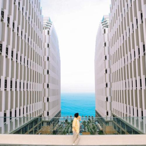 a man walking between two tall buildings near the ocean at Apec Mandala Imperial Ocean Tower Mui Ne in Mui Ne
