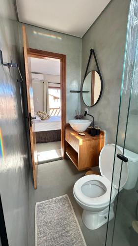 a bathroom with a toilet and a sink and a mirror at Duplex 2 Suites Pool Barbecue Air in Santa Cruz Cabrália