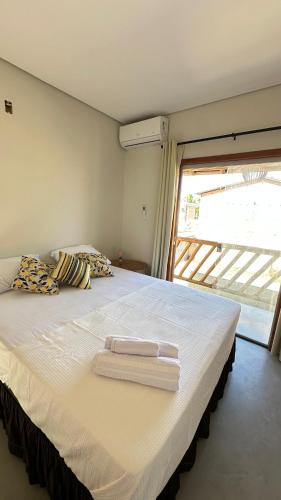a bedroom with a large bed with two towels on it at Duplex 2 Suites Pool Barbecue Air in Santa Cruz Cabrália