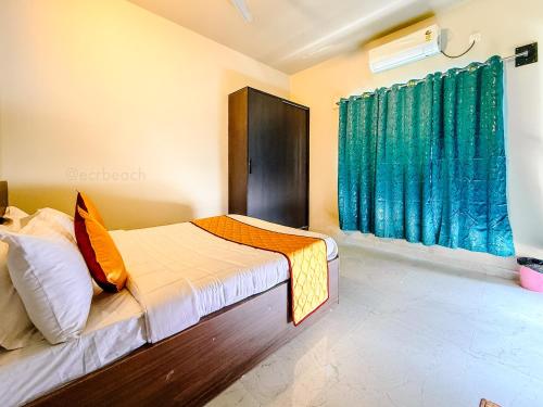 a bedroom with a bed and a window with green curtains at SeaLara Resorts in Covelong