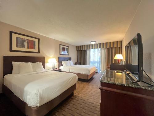 a hotel room with two beds and a flat screen tv at Derby Hotel & Suites in Clarksville