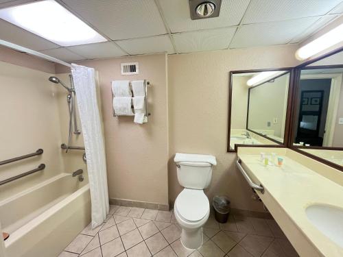 a bathroom with a toilet and a tub and a sink at Derby Hotel & Suites in Clarksville