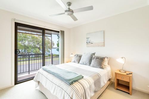 a white bedroom with a bed and a window at Amarco Spacious Riverfront with Sunset Views in Iluka