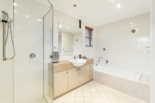 a white bathroom with a sink and a shower at Amarco Spacious Riverfront with Sunset Views in Iluka